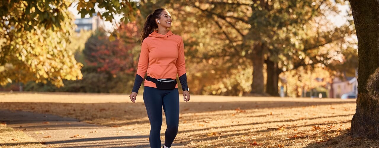 Happy athletic woman taking a walk through autumn park.